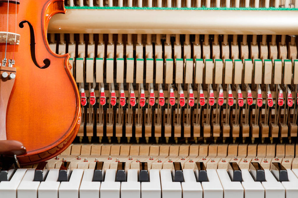 klassieke bruine viool op de close-up beeld van grand piano toetsen en interieur achtergrond - Foto, afbeelding