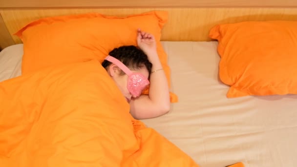 Zbliżenie wideo 4k spania młoda kobieta ubrana maska opaskę. Budzi się i usuwa opatrunek. Świadomość, że on ma Zaspałem - Materiał filmowy, wideo