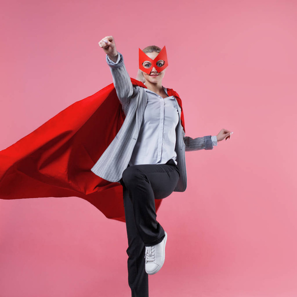 Young attractive woman superhero. Girl in a business suit and a mask with red cloak of hero. - Fotoğraf, Görsel