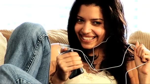 Beautiful latin girl on the sofa with her MP3 player - Video, Çekim
