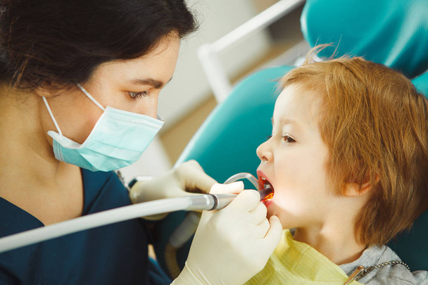 Boy drills the tooth of female dentist. Little child on dental chair. - Fotó, kép