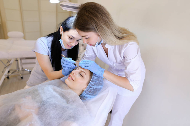 Cosmetologista e enfermeira removendo cravos pela limpeza de rosto manual para a mulher
. - Foto, Imagem