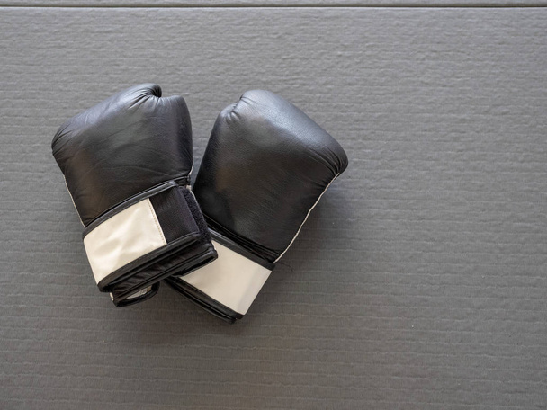 Widok wysoki czarne rękawice bokserskie, siedząc na szary mat boksu  - Zdjęcie, obraz