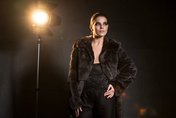 Sexy woman in a fashionable fir coat in the dark - Foto, afbeelding
