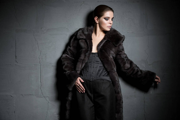 Beautiful brunette in fur coat in the dark - Foto, afbeelding