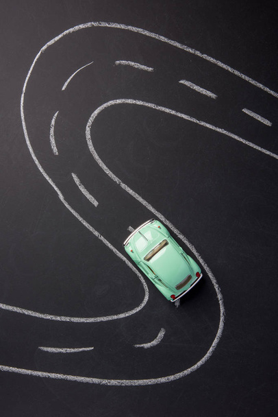 Toy car green on the road chalked on black chalkboard - Photo, Image