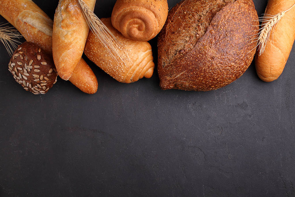 Pile of fancy bread on black stone background - Photo, Image