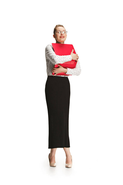 Full length portrait of a smiling female teacher holding a laptop isolated against white background - Foto, imagen
