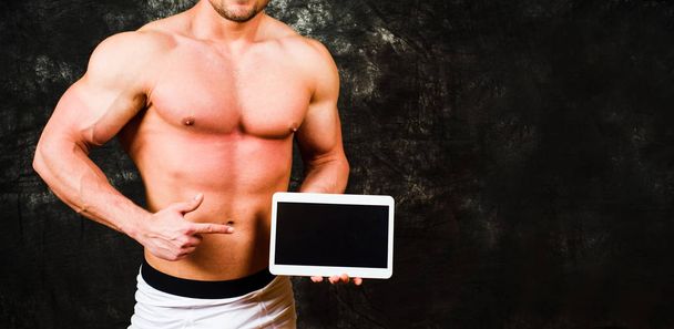 Bodybuilder tenant un appareil tablette avec espace de copie
 - Photo, image
