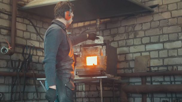 Blacksmith with gloves in forge makes steel knife - Foto, Imagen