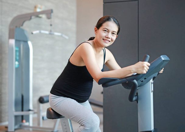 Pregnant woman exercise on the bicycle in sports hall. - Foto, Imagem
