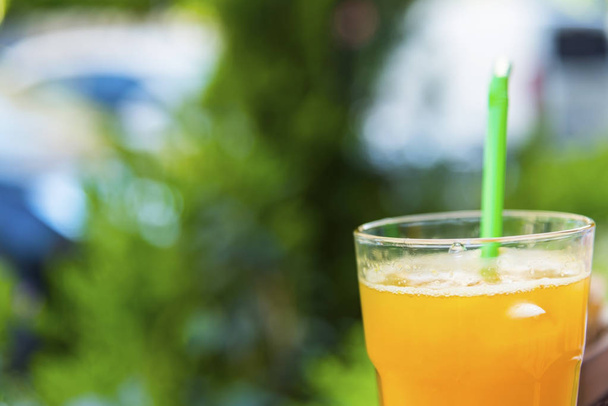 Orange juice with green pipet outdoors  - Foto, immagini