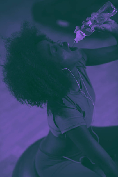 young afro american woman in gym on pilates workout break teaking breath and fresh drinking  water duo tone filter - Fotoğraf, Görsel
