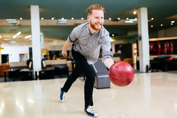 Handsome man bowling in club and throwing ball - Foto, immagini