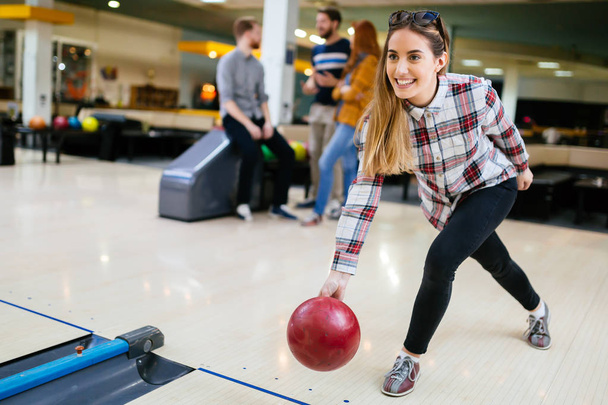 Beautiful woman bowling with friends getting ready to throw ball - Photo, Image