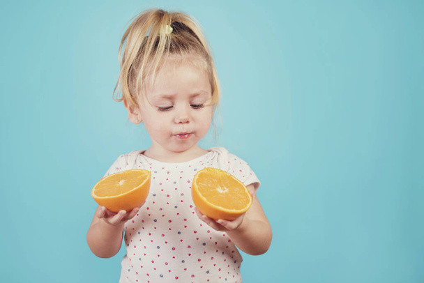 青の背景にオレンジを食べる赤ちゃん - 写真・画像