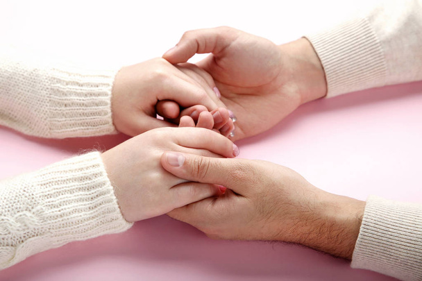 weibliche und männliche Hand halten einander auf rosa Hintergrund - Foto, Bild