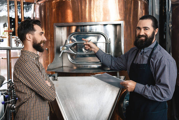 Two bearded brewers inspecting equipment of brewery for production of craft beer - Foto, Bild