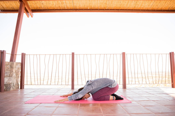 Mujer joven flexible haciendo ejercicios de yoga de pose infantil en un estudio de fitness
 - Foto, imagen