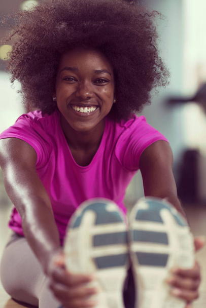 happy young african american woman in a gym stretching and warming up before workout - Foto, Imagem