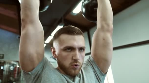 Portrait of male athlete, who is doing exercises with kettles in modern gym. - Filmati, video