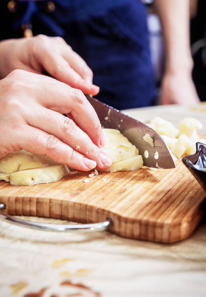 Womans hand with a knife cutting the boiling potatoes - Photo, Image
