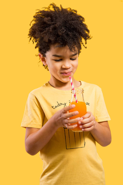 Cute little boy drinking orange juice with a straw - 写真・画像