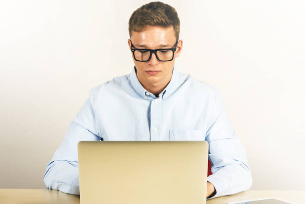 Retrato de un joven sentado en su escritorio en la oficina usando una computadora portátil
 - Foto, Imagen