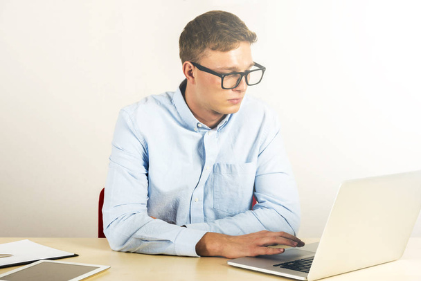 Портрет молодого чоловіка, який сидить за своїм столом в офісі, використовуючи ноутбук
 - Фото, зображення