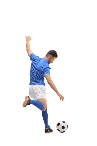 Full length rear view shot of a soccer player kicking a football isolated on white background - 写真・画像