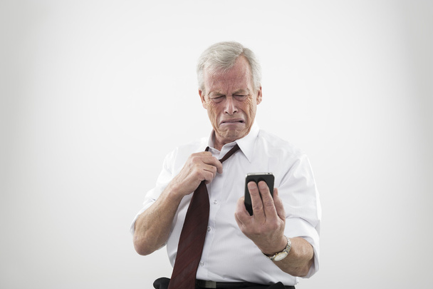 Uomo anziano che reagisce con disgusto al suo cellulare
 - Foto, immagini