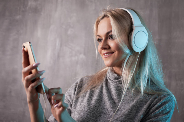 Young and attractive woman listening to music in the mobile app. Girl music lover. - Фото, зображення
