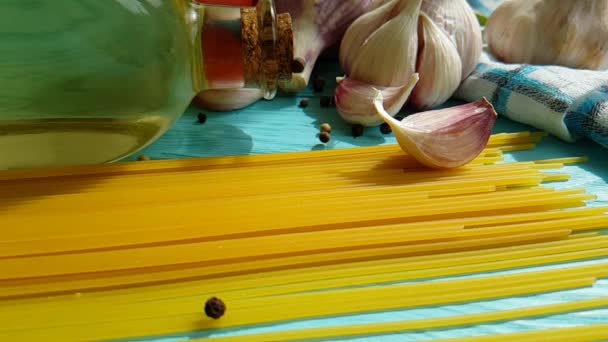 Spaghetti, Öl in der Flasche, Knoblauch, Tomate, schwarzer Pfeffer auf blauem Holzgrund, Zeitlupenschießen - Filmmaterial, Video