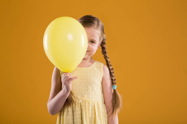 Ευτυχισμένη κοπέλα στο φόρεμα, κρατά κίτρινα μπαλόνια - Φωτογραφία, εικόνα