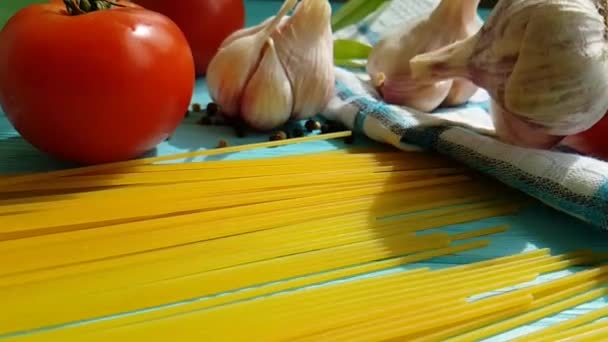 Spaghetti, Öl in der Flasche, Knoblauch, Tomate, schwarzer Pfeffer auf blauem Holzgrund, Zeitlupenschießen - Filmmaterial, Video
