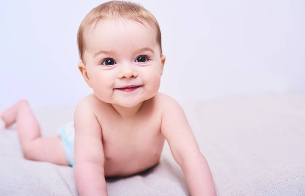 Portrait of cute crawling baby on bed in room - Foto, Bild