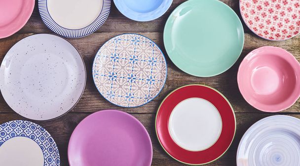 Conjunto de diferentes platos de colores sobre fondo de madera
 - Foto, Imagen