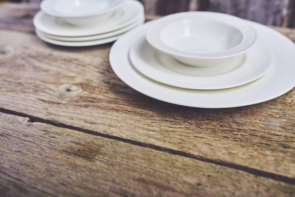 木製のテーブルに新しいきれいな白い皿のセット - 写真・画像