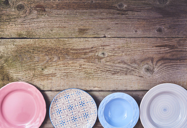 Набір різних барвистих посуду на фоні дерев'яної дошки
 - Фото, зображення