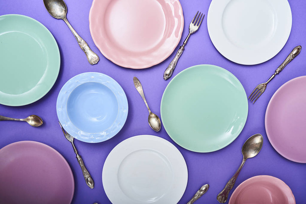 Σετ από διαφορετικά πολύχρωμα πιάτα με μαχαιροπίρουνα μοβ φόντο - Φωτογραφία, εικόνα