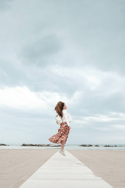 A girl in a flying dress is walking along the coast - Foto, afbeelding