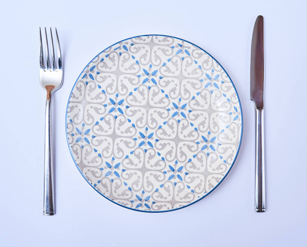 Вид сверху пустой круглой тарелки с вилкой и ножом. Назначение столика в ресторане
 - Фото, изображение