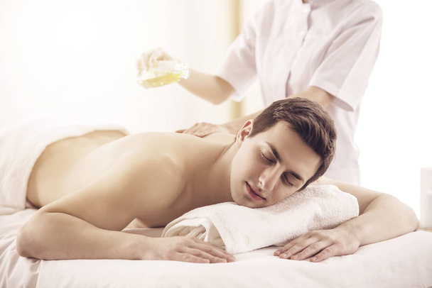 Masseur doing massage on man body with spa oil in beauty salon - Photo, Image