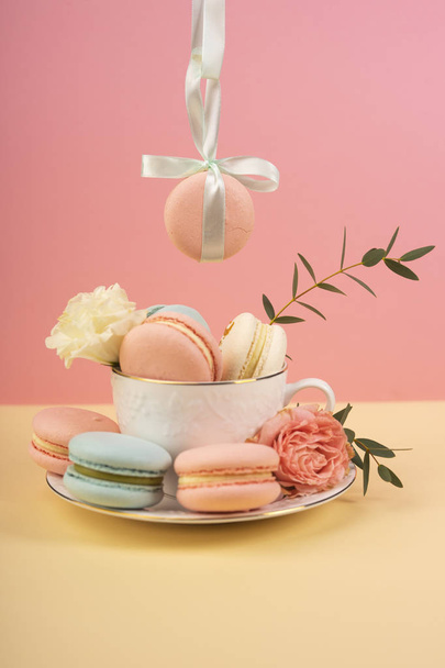 Macaroons cake are placed in a cup with buds of a carnation and  - Zdjęcie, obraz