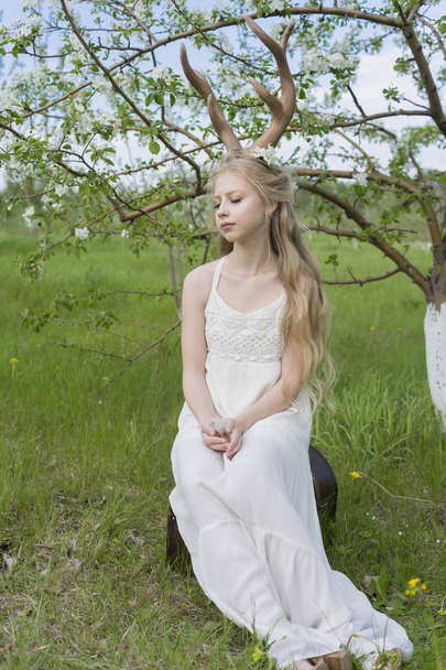 Teen beautiful blonde girl wearing white dress with deer horns o - Φωτογραφία, εικόνα