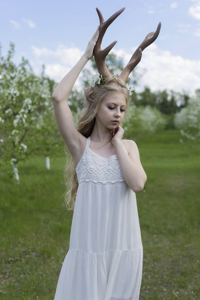 Teen beautiful blonde girl wearing white dress with deer horns o - Fotoğraf, Görsel