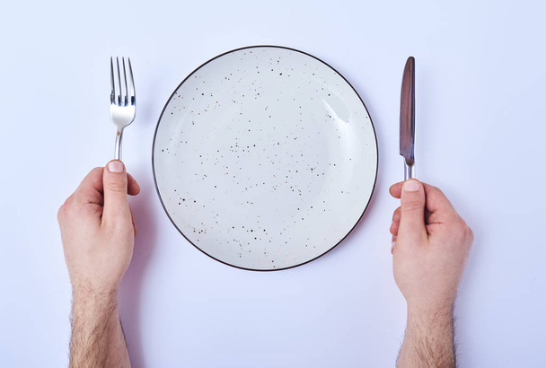 Top view of male hands with cutlery and empty round plate on table - Photo, Image