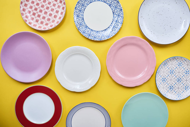Σετ από διαφορετικά πολύχρωμα πιάτα πάνω από φωτεινό έγχρωμο φόντο - Φωτογραφία, εικόνα