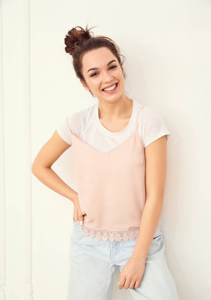 Retrato de jovem linda morena modelo da menina com maquiagem nua em roupas hipster coloridas de verão rosa posando perto da parede. Enlouquecendo e olhando feliz na câmera
  - Foto, Imagem