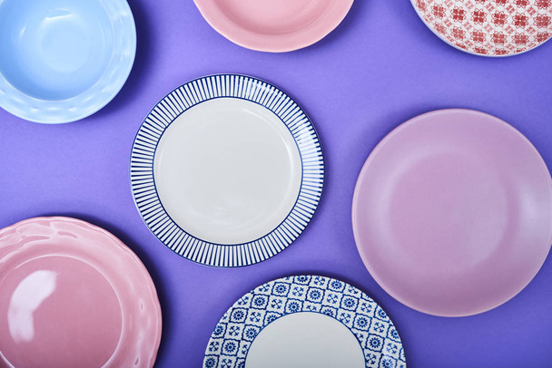 Σετ από διαφορετικά πολύχρωμα πιάτα πάνω από φωτεινό έγχρωμο φόντο - Φωτογραφία, εικόνα